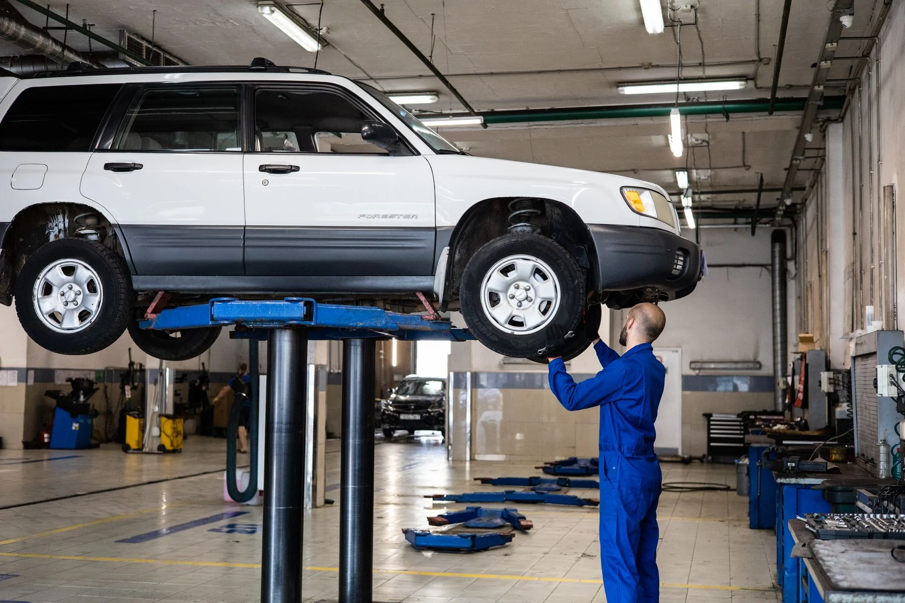 Mechanic checking a vehicle raised in a workshop