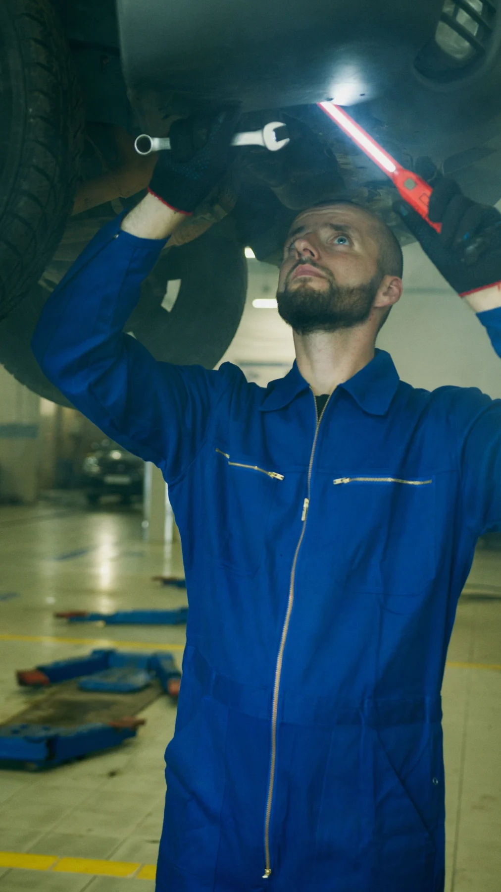 Mechanic inspecting the underside of a raised vehicle